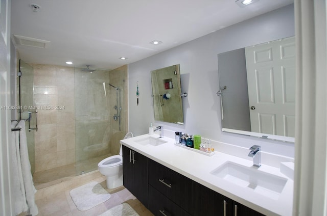 bathroom with a shower with door, vanity, toilet, and tile patterned floors