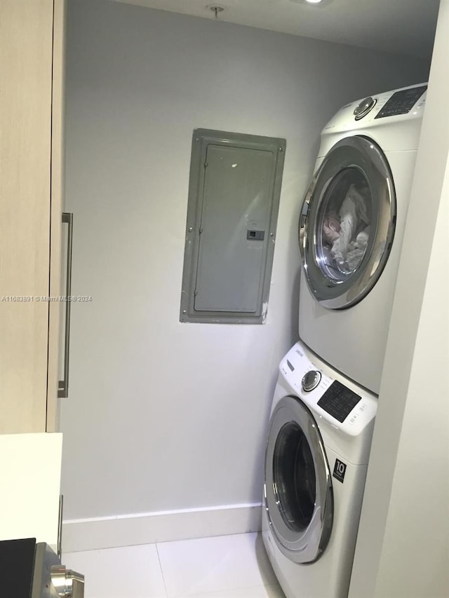 laundry room featuring stacked washing maching and dryer, electric panel, and light tile patterned floors