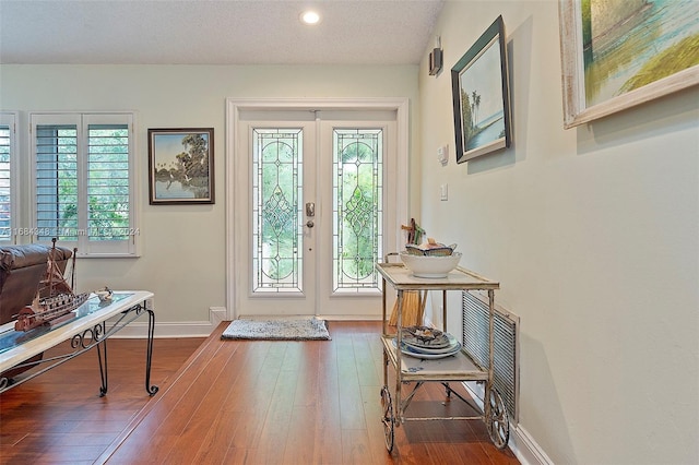 entrance foyer featuring french doors, hardwood / wood-style flooring, and a textured ceiling