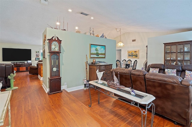 living room featuring hardwood / wood-style flooring, a textured ceiling, and lofted ceiling