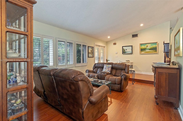 living room featuring a textured ceiling, wood-type flooring, and lofted ceiling