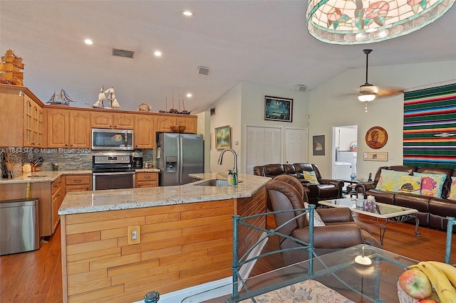 kitchen with tasteful backsplash, appliances with stainless steel finishes, sink, light hardwood / wood-style floors, and vaulted ceiling