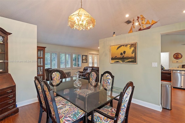 dining area with a notable chandelier, a textured ceiling, and dark hardwood / wood-style flooring