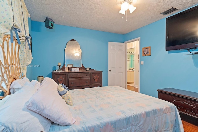 bedroom with light hardwood / wood-style floors, a textured ceiling, and ceiling fan