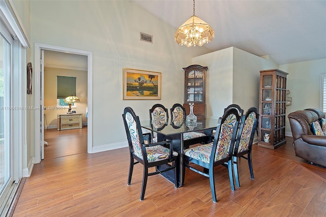 dining room with an inviting chandelier, vaulted ceiling, and light hardwood / wood-style floors