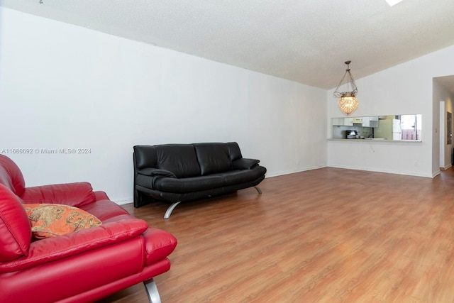 living room featuring a textured ceiling, wood-type flooring, vaulted ceiling, and a chandelier