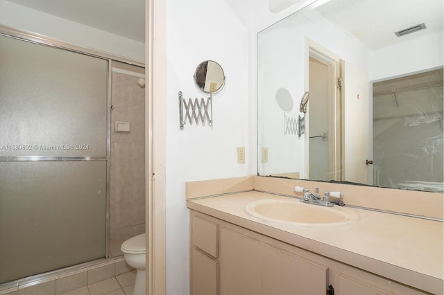 bathroom featuring toilet, vanity, tile patterned floors, and a shower with door