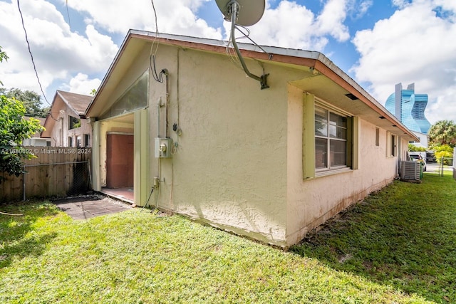 view of side of property with a yard and central AC unit