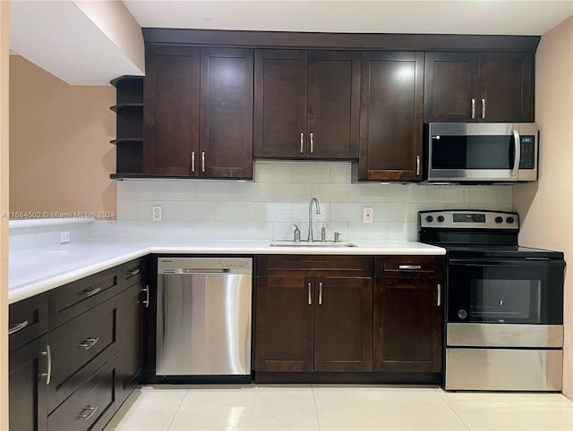 kitchen with dark brown cabinetry, sink, stainless steel appliances, decorative backsplash, and light tile patterned floors