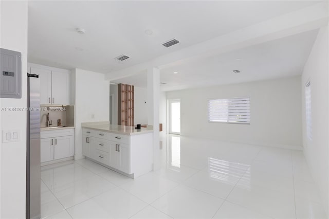 kitchen with light tile patterned flooring, white cabinetry, sink, electric panel, and decorative backsplash