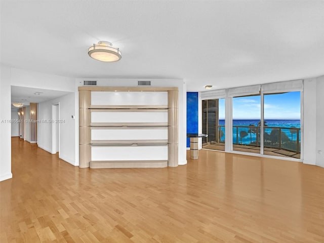 unfurnished living room with a wall of windows and hardwood / wood-style floors