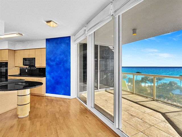 kitchen with a water view, backsplash, light wood-type flooring, and light brown cabinets