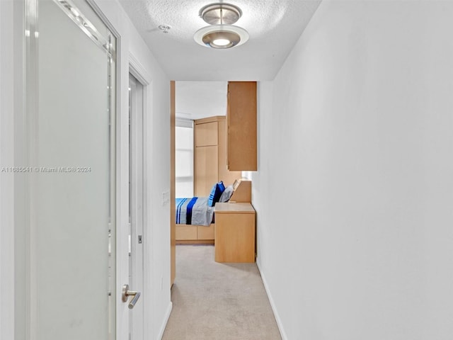 hallway featuring light carpet and a textured ceiling