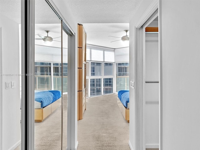 hallway featuring a textured ceiling and light colored carpet