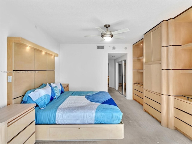 bedroom with a textured ceiling, light colored carpet, and ceiling fan