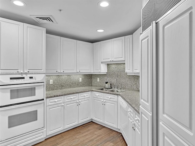 kitchen with white cabinetry, light stone countertops, light wood-type flooring, and white appliances