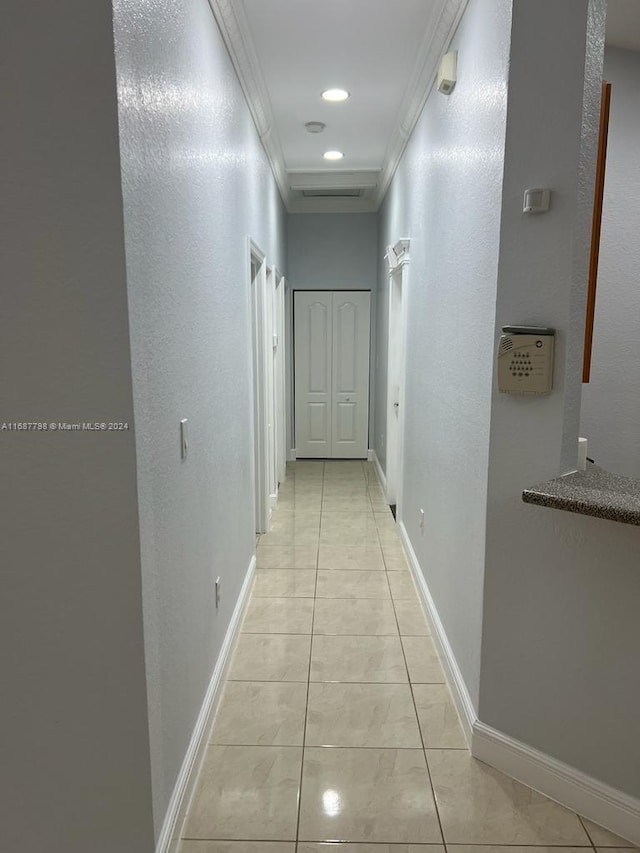 corridor featuring light tile patterned floors and crown molding