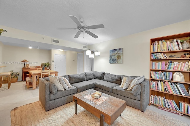 living room featuring ceiling fan, light tile patterned flooring, and a textured ceiling