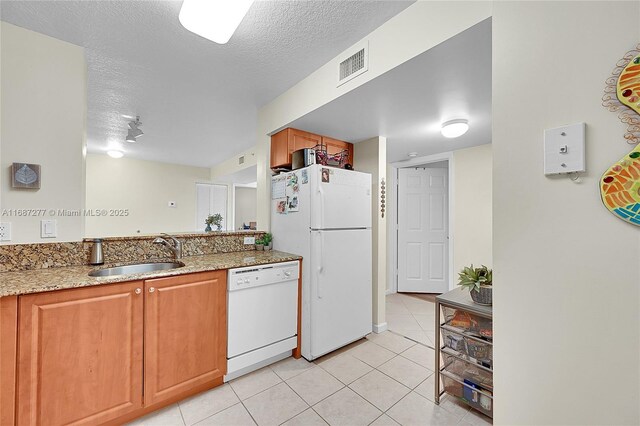 519 E Sheridan St Unit 106, Dania Beach, FL 33004 - kitchen with white appliances, light tile patterned flooring, a textured ceiling, light stone counters, and brown cabinetry