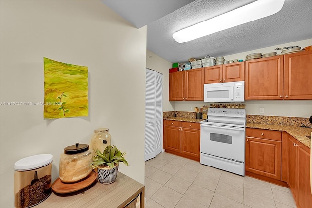 519 E Sheridan St Unit 106, Dania Beach, FL 33004 - kitchen with white appliances, light tile patterned floors, light stone countertops, brown cabinetry, and a textured ceiling