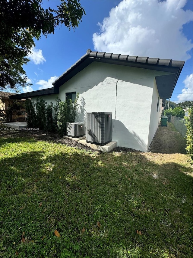 back of house with a lawn and central air condition unit