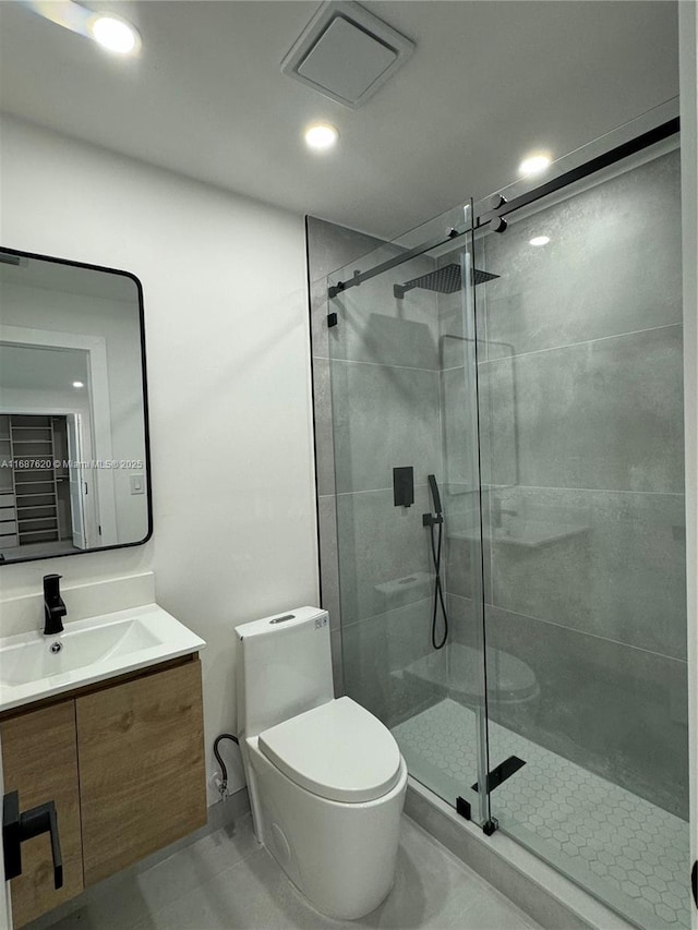 bathroom featuring tile patterned flooring, vanity, a shower with shower door, and toilet