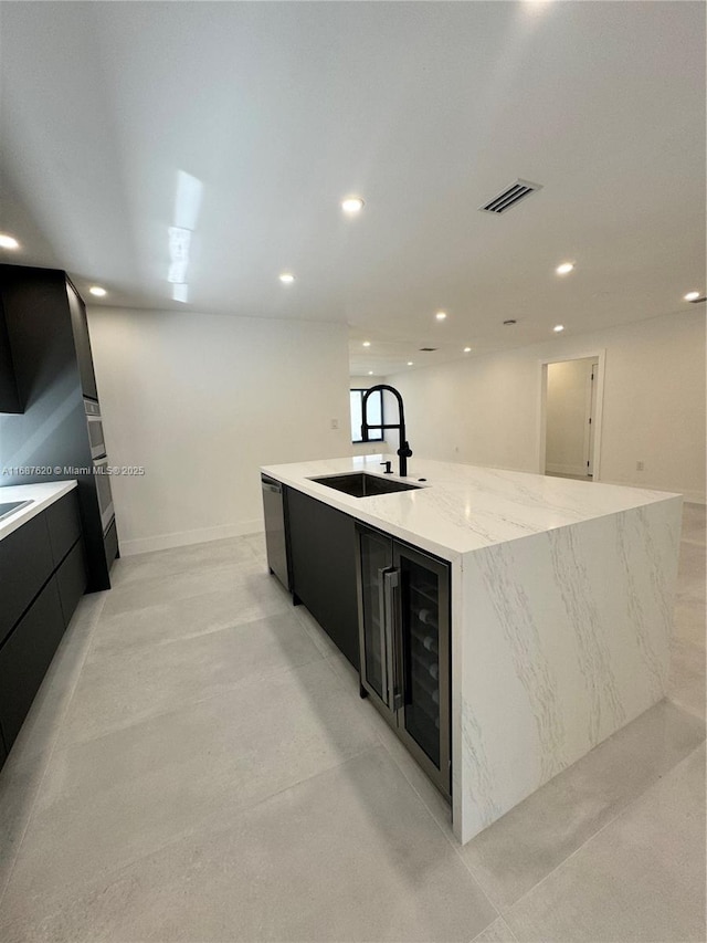 kitchen with sink, a large island with sink, stainless steel dishwasher, beverage cooler, and light stone countertops