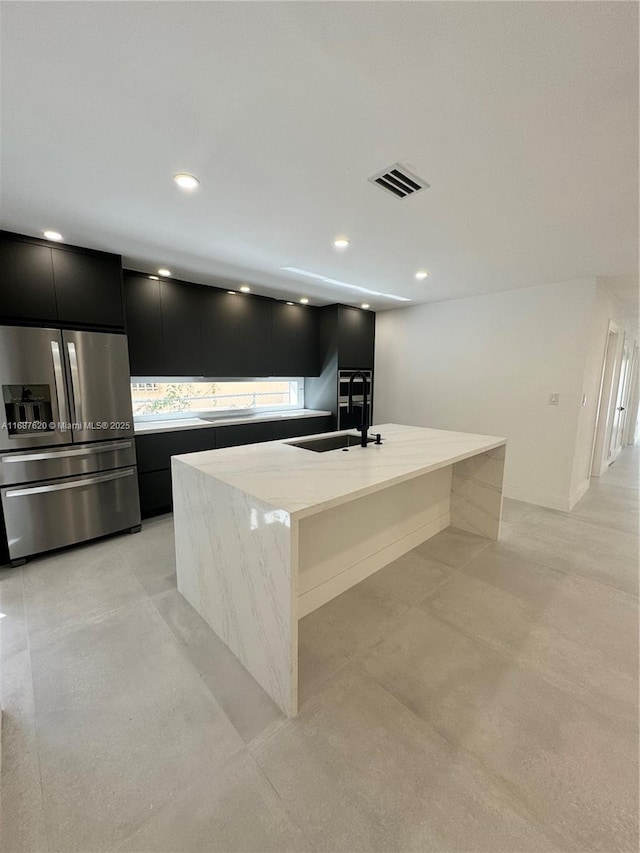 kitchen featuring sink, a kitchen island with sink, and stainless steel fridge with ice dispenser