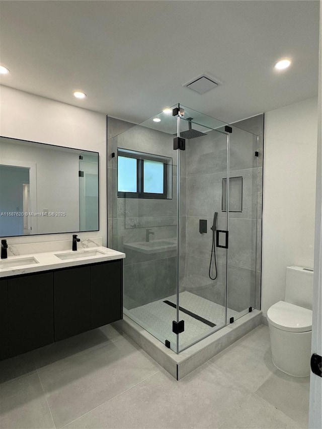 bathroom featuring tile patterned floors, vanity, toilet, and a shower with shower door