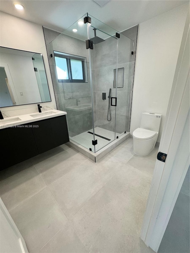 bathroom featuring a shower with door, vanity, tile patterned floors, and toilet