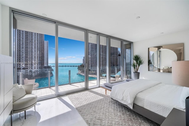 bedroom with a water view, expansive windows, and access to exterior