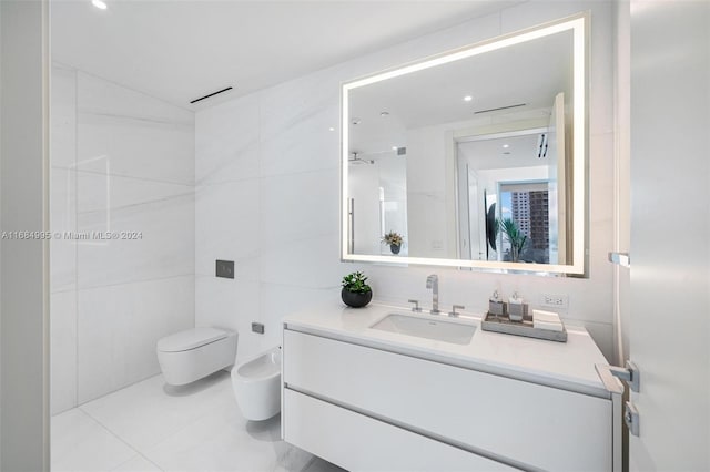 bathroom with toilet, tile patterned flooring, a bidet, vanity, and tile walls