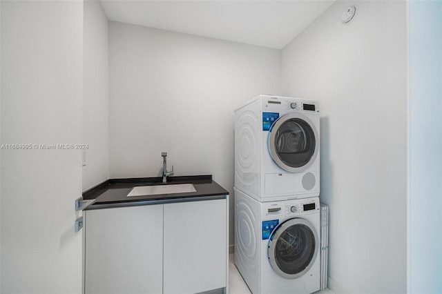 clothes washing area with cabinets, sink, and stacked washer and clothes dryer