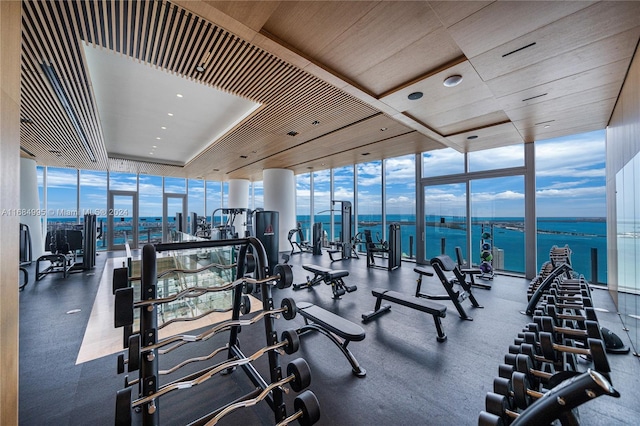 exercise room with a wall of windows and a water view