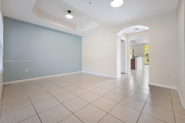 spare room featuring a raised ceiling and light tile patterned floors