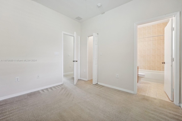 unfurnished bedroom with ensuite bath and light colored carpet