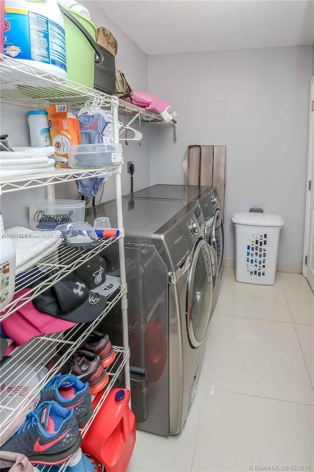 clothes washing area featuring washer and dryer, a textured ceiling, and tile patterned flooring