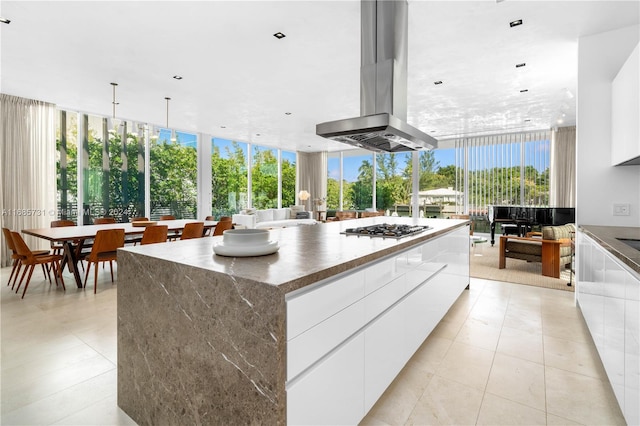 kitchen featuring a spacious island, a wealth of natural light, white cabinetry, and island exhaust hood