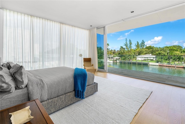 bedroom featuring a water view, hardwood / wood-style flooring, and access to exterior