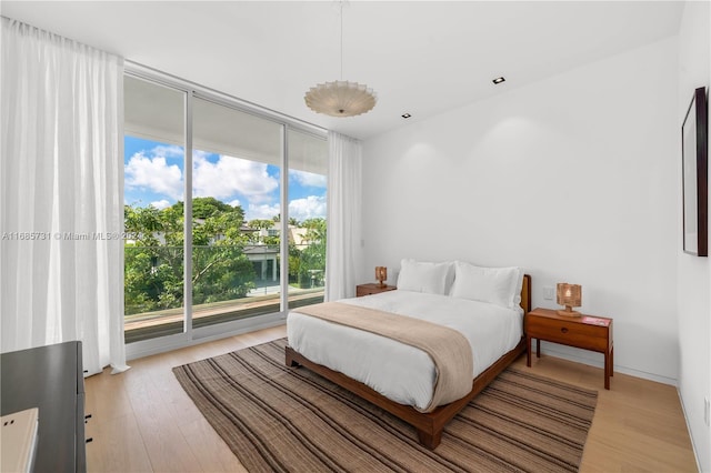 bedroom featuring access to exterior, light hardwood / wood-style floors, expansive windows, and multiple windows