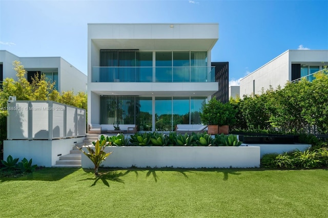 rear view of property featuring a balcony and a yard