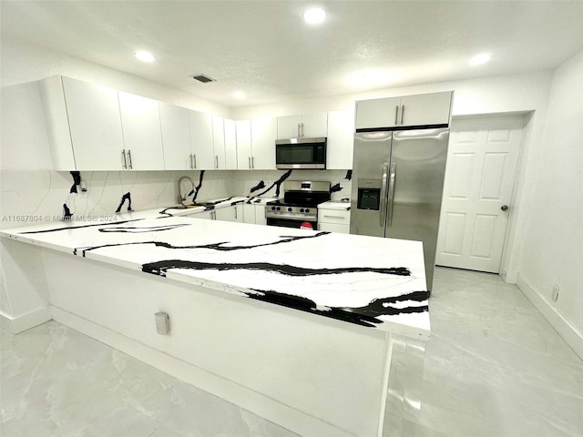 kitchen featuring backsplash, white cabinets, sink, appliances with stainless steel finishes, and kitchen peninsula