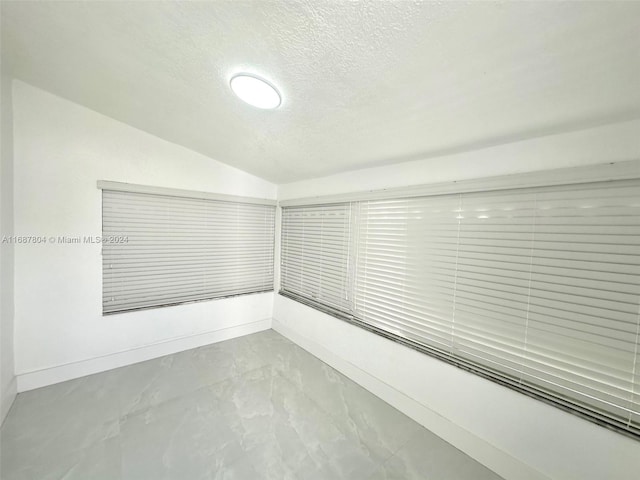 empty room with a textured ceiling and lofted ceiling