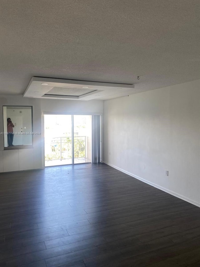 empty room featuring a textured ceiling and dark hardwood / wood-style floors