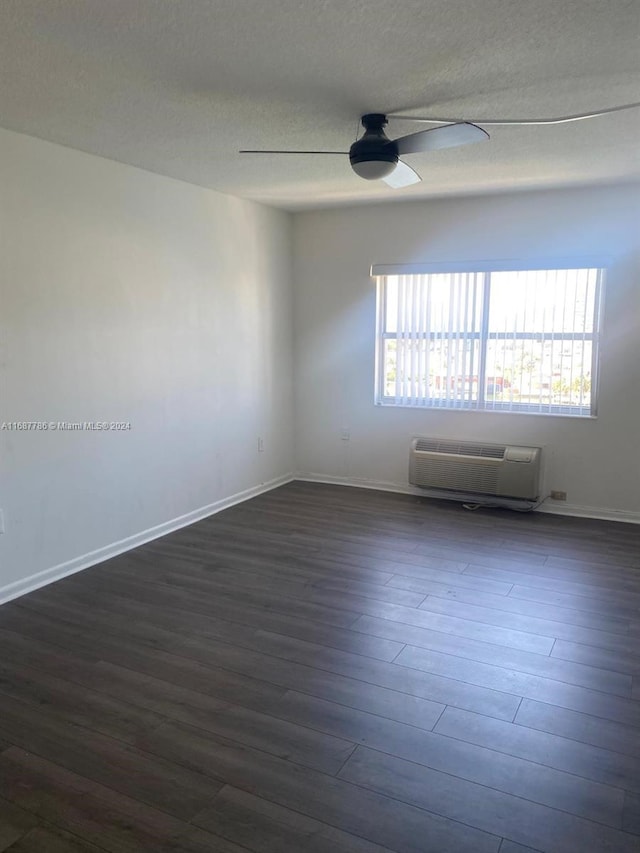 unfurnished room with a wealth of natural light, an AC wall unit, and dark hardwood / wood-style flooring