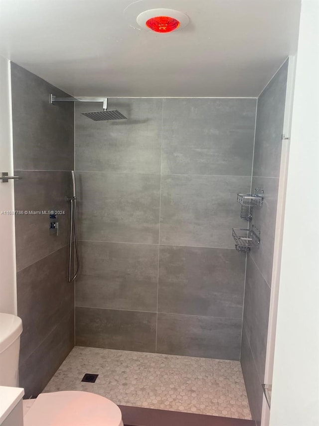 bathroom featuring vanity, toilet, and a tile shower