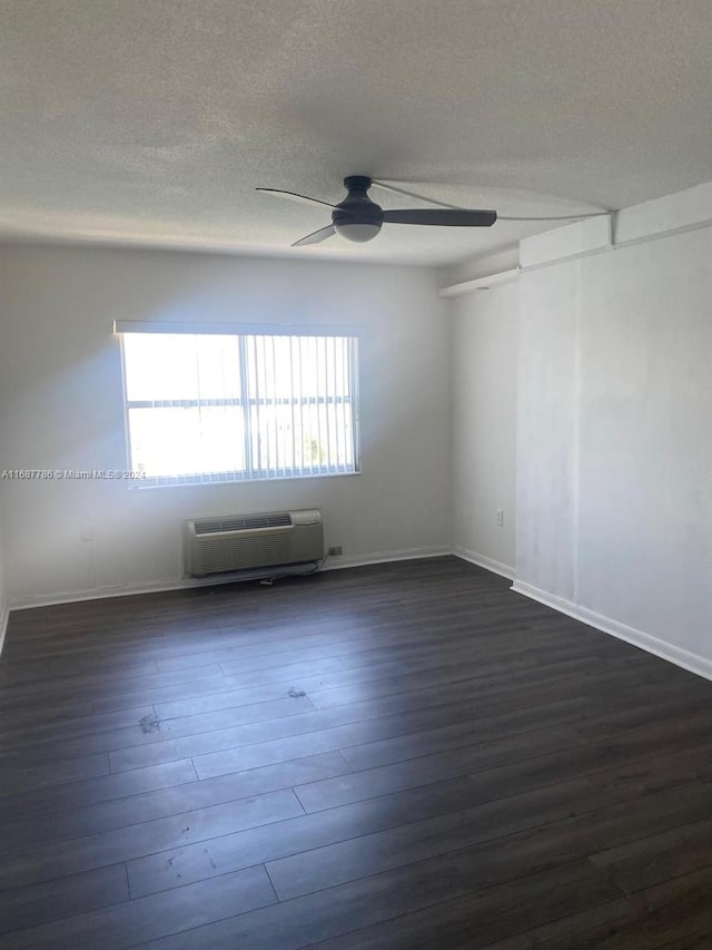 spare room featuring a wall mounted AC, dark wood-type flooring, a textured ceiling, and ceiling fan