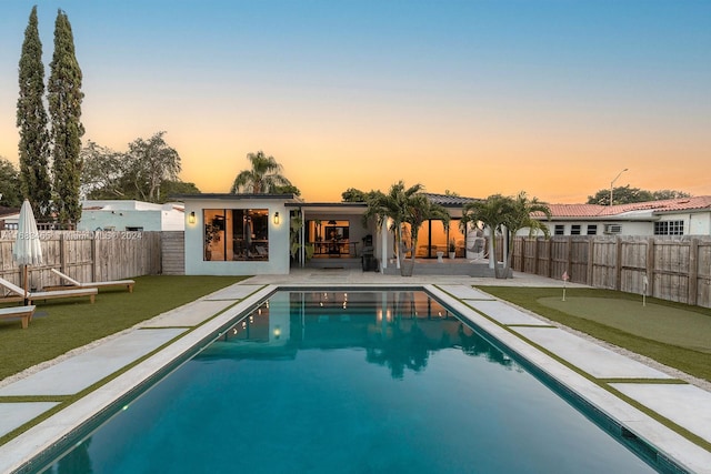 pool at dusk featuring a patio area