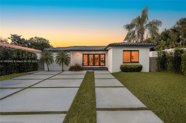 view of front of house featuring french doors and a lawn