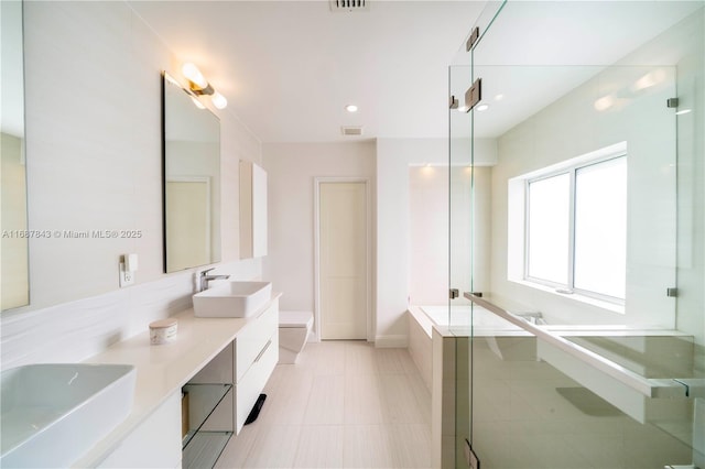 full bathroom featuring double vanity, a tub to relax in, a sink, and visible vents